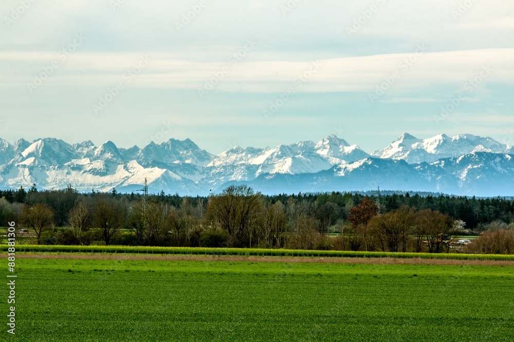 View of the Alpine foothills from the outskirts of Munich. In the foreground are green fields and forests without leaves. Mountains are not in focus View of the Alpine foothills from the outskirts of Munich. In the foreground are green fields and forests without leaves. Mountains are not in focus