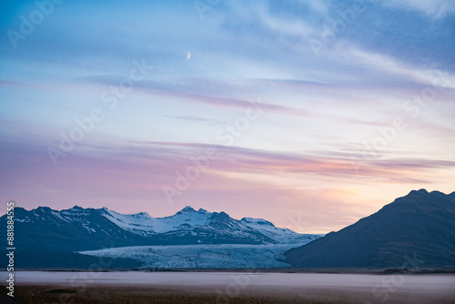 Obraz na płótnie Stunning view of a dramatic landscape with some snowy mountains and a glacier in the distance during a beautiful sunrise, Iceland. w salonie