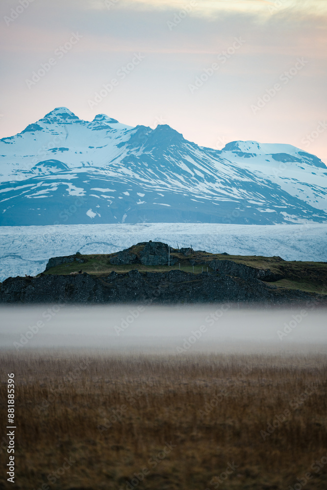 Stunning view of a dramatic landscape with some snowy mountains and a glacier in the distance during a beautiful sunrise, Iceland.