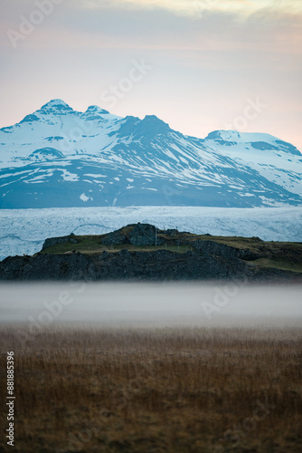 Obraz na płótnie Stunning view of a dramatic landscape with some snowy mountains and a glacier in the distance during a beautiful sunrise, Iceland. w salonie