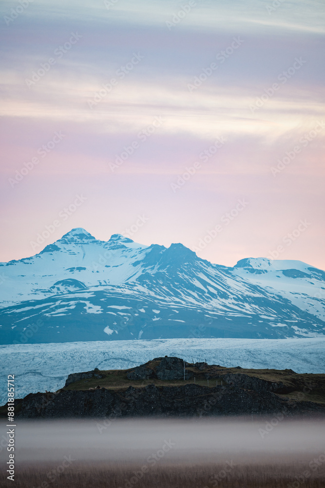 Stunning view of a dramatic landscape with some snowy mountains and a glacier in the distance during a beautiful sunrise, Iceland.