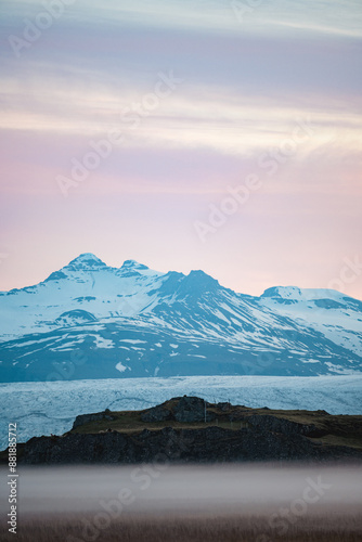 Obraz na płótnie Stunning view of a dramatic landscape with some snowy mountains and a glacier in the distance during a beautiful sunrise, Iceland. w salonie