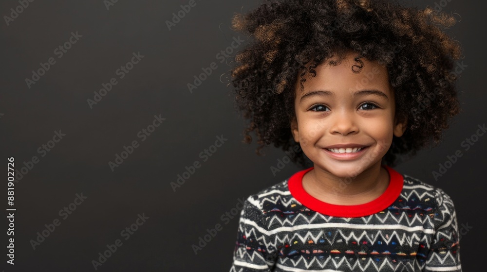 A young boy with curly hair smiles brightly at the camera A young boy with curly hair smiles brightly at the camera