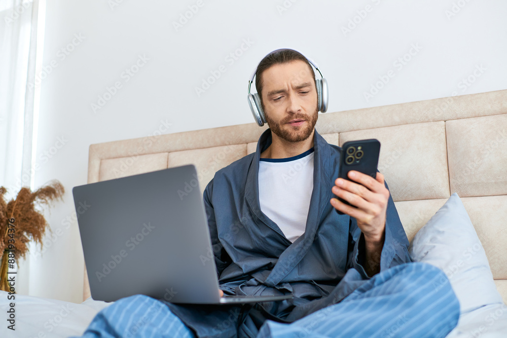 A man enjoys the morning, using a laptop and headphones on a bed. A man enjoys the morning, using a laptop and headphones on a bed.