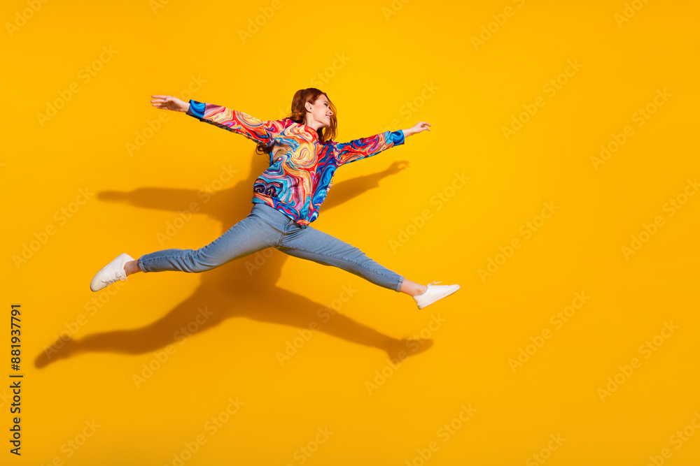 Full size photo of cheerful positive girl dressed print shirt jeans jumping run to empty space isolated on yellow color background