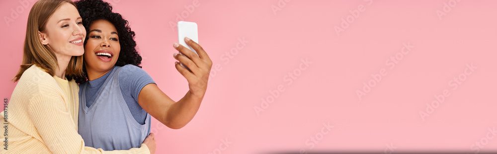 Two diverse women in casual attire taking a selfie with a cell phone. Two diverse women in casual attire taking a selfie with a cell phone.