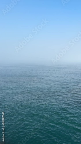 Blue sea waves and sky at misty morning, vertical video.