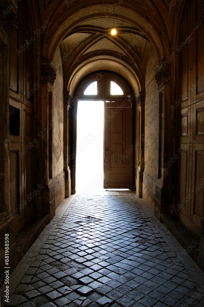 Dimly lit medieval corridor with an arched ceiling and an open door. Budapest, Hungary Dimly lit medieval corridor with an arched ceiling and an open door. Budapest, Hungary