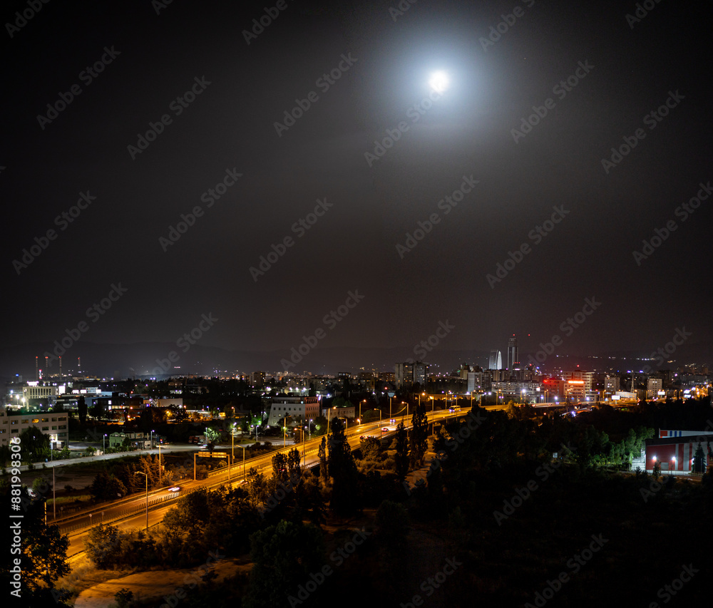 Naklejka premium The bright moon shines over the night lights of Sofia, the capital city of Bulgaria, in Eastern Europe.