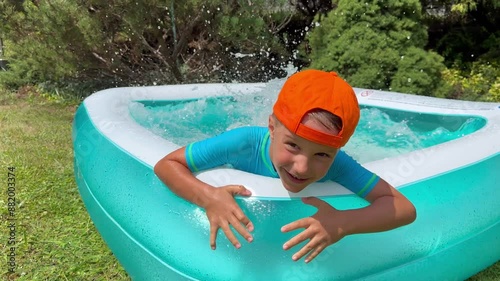 Happy smiling boy swimming into swimming pool. Summer water fun. Child play in outdoor pool. Sun protection. Family sunny holidays. 