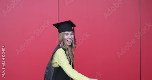 Young beautiful blond female in graduation cap with emotional facial expression on red background. Happy to finish school, college or university video footage 4k