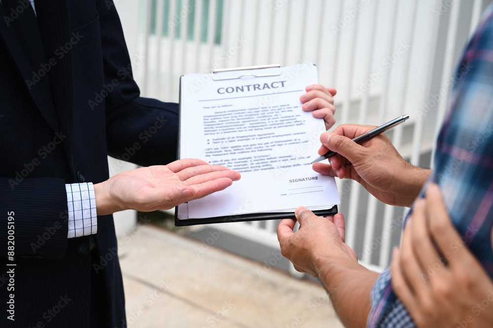 Sealing the Deal, A close-up of a new homeowner signing the contract, guided by the real estate agent, marking the final step in the home buying process to ownership