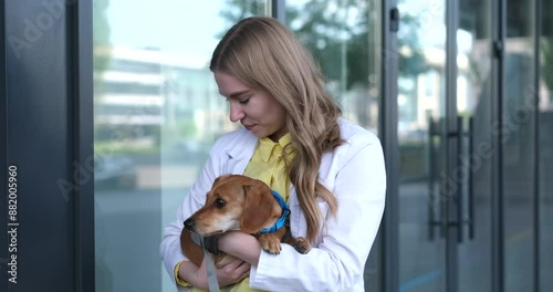 Young veterinarian smiling and holding dog near the vet clinic entrance. Healthy dog, diagnostic, treatment of domestic animals. video footage 4k