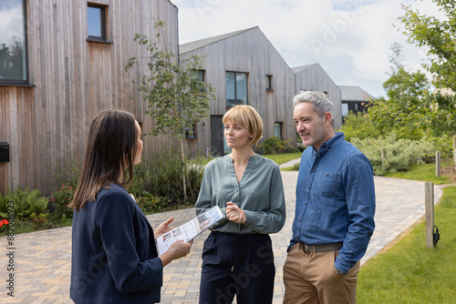 Real estate agent giving property details of an eco home to a mature couple photo