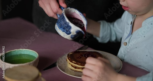 Little boy adorable having breakfast with pancakes with tea and apples at home. Cute weekend with sweet tasty food and emotional child. video footage 4k