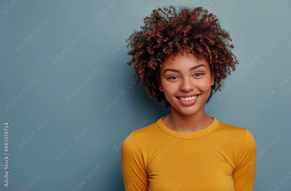 Smiling Woman With Curly Hair Wearing Yellow Shirt Against Blue Background Smiling Woman With Curly Hair Wearing Yellow Shirt Against Blue Background