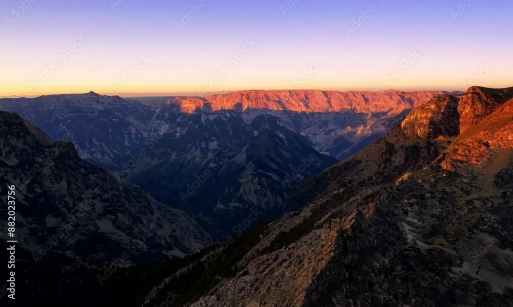 The mountains are covered in a beautiful orange glow as the sun sets. The sky is a mix of pink and purple hues, creating a serene and peaceful atmosphere The mountains are covered in a beautiful orange glow as the sun sets. The sky is a mix of pink and purple hues, creating a serene and peaceful atmosphere