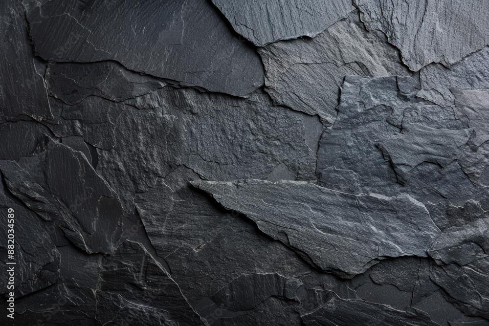 Close-up of a textured black slate stone surface with natural layers and cracks, perfect for backgrounds or textures in design projects. Close-up of a textured black slate stone surface with natural layers and cracks, perfect for backgrounds or textures in design projects.
