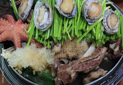 Close-up of Korean food Haesintang(Chicken and Seafood Soup) with raw abalone, octopus, water parsley and mushroom on the pot at a restaurant, South Korea
 photo