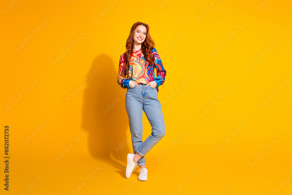 Full length photo of lovely young lady posing model hands pockets dressed stylish colorful garment isolated on orange color background Full length photo of lovely young lady posing model hands pockets dressed stylish colorful garment isolated on orange color background