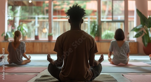Man Leading Yoga Class in a Studio Setting With Other Participants in Lotus Pose