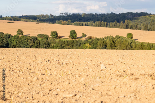 Plowed field and forest in the background. Rural landscape in Czechia.