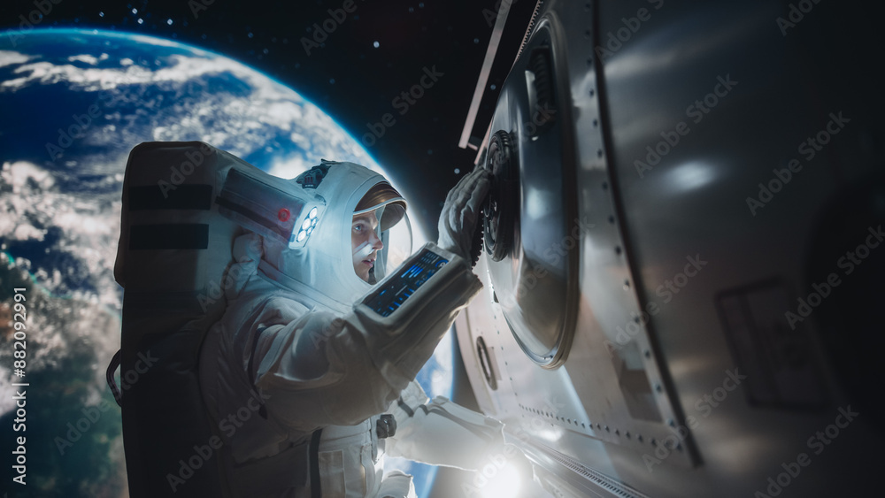 Portrait of a Young Astronaut Posing in a Space Suit During a Spacewalk Outside a Spaceship, Satellite or a Station. Spaceman Closing Down The Entrance Hatch Of The International Space Station Portrait of a Young Astronaut Posing in a Space Suit During a Spacewalk Outside a Spaceship, Satellite or a Station. Spaceman Closing Down The Entrance Hatch Of The International Space Station