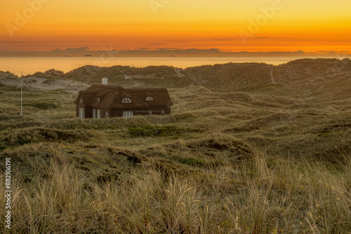 Obraz na płótnie thatched lonely old house with rye grass in the foreground at sunset w salonie
