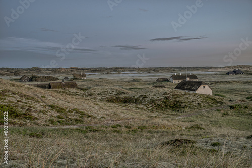 Obraz na płótnie thatched houses scattered in the dunes when the fog settles in the evening w salonie
