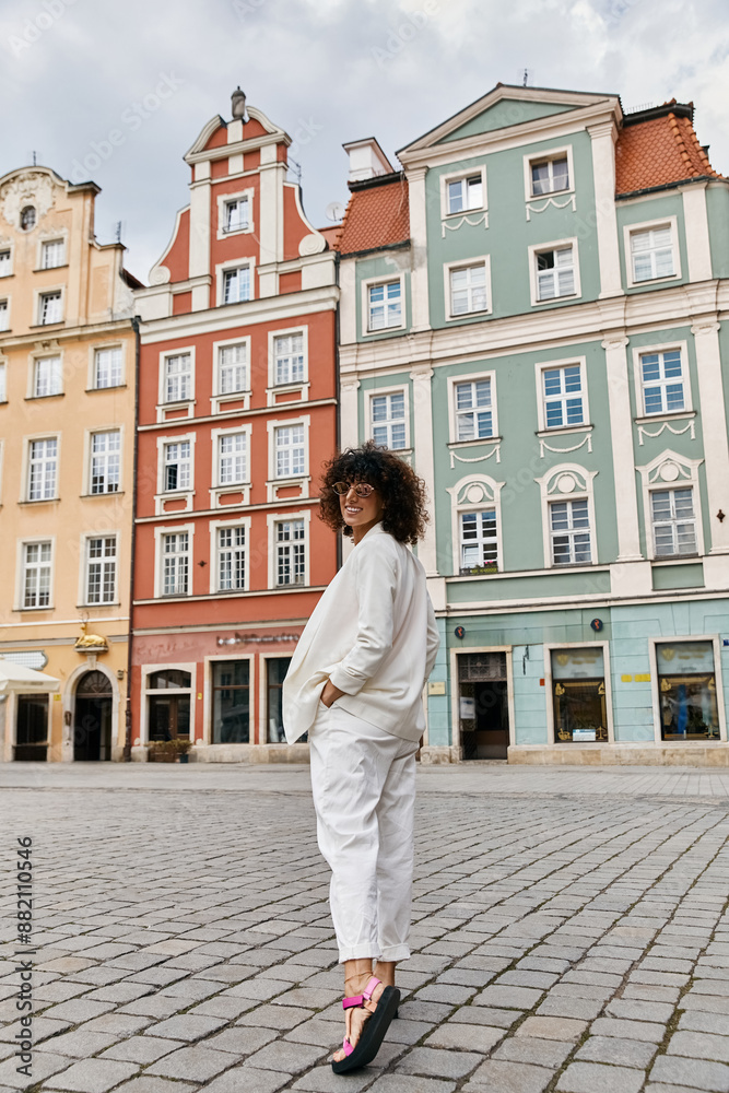 A woman in a white outfit strolls through a European town square, admiring the colorful buildings. A woman in a white outfit strolls through a European town square, admiring the colorful buildings.