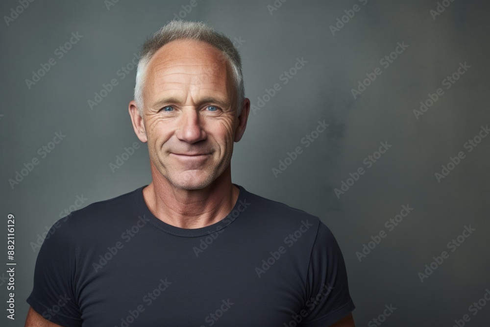 Portrait of a grinning man in his 50s donning a classy polo shirt in front of bare concrete or plaster wall Portrait of a grinning man in his 50s donning a classy polo shirt in front of bare concrete or plaster wall