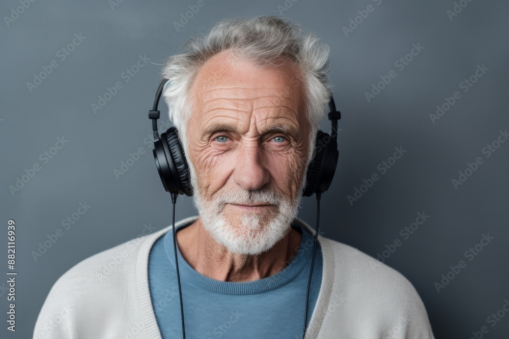 Portrait of a tender man in his 70s wearing a cozy sweater in bare concrete or plaster wall Portrait of a tender man in his 70s wearing a cozy sweater in bare concrete or plaster wall