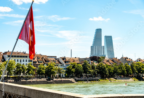 Rhine river in Basel with a Swiss flag in the Foreground and the Roche Towers in the Background