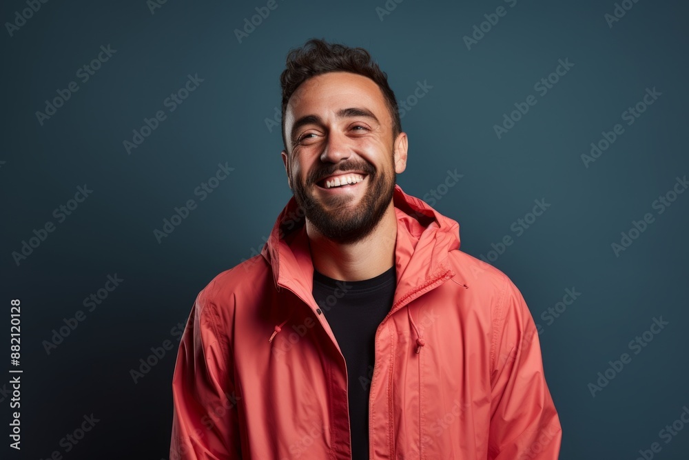 Obraz premium Portrait of a happy man in his 30s wearing a functional windbreaker on blank studio backdrop
