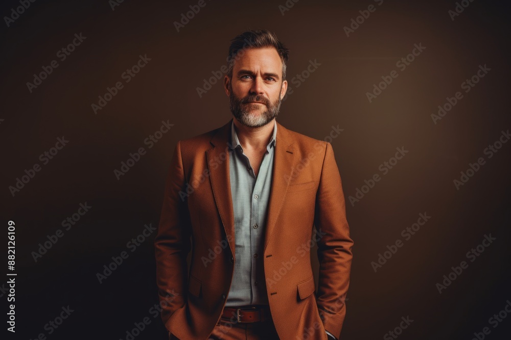 Fototapeta premium Portrait of a content man in his 40s dressed in a stylish blazer while standing against light wood minimalistic setup