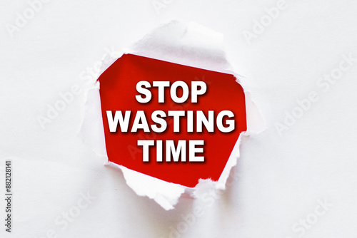 A red sign with the message Stop Wasting Time is visible through a torn hole in a white sheet of paper.