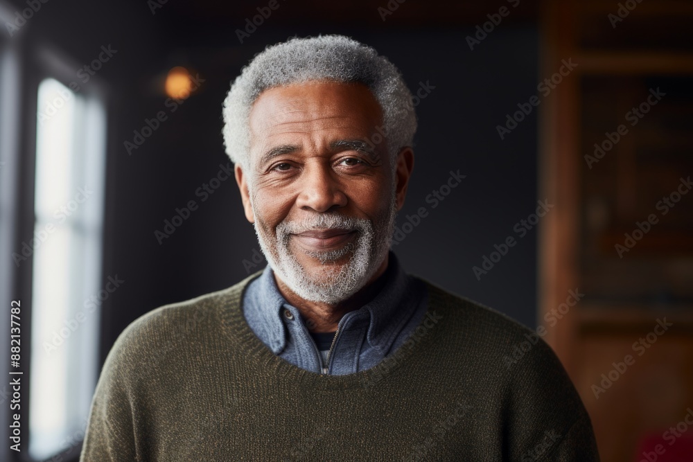 Portrait of a content afro-american man in his 80s wearing a cozy sweater isolated on empty modern loft background Portrait of a content afro-american man in his 80s wearing a cozy sweater isolated on empty modern loft background