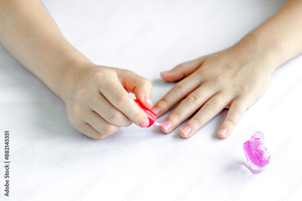 Close-up of a little girl's hands painting her nails with pink polish Close-up of a little girl's hands painting her nails with pink polish