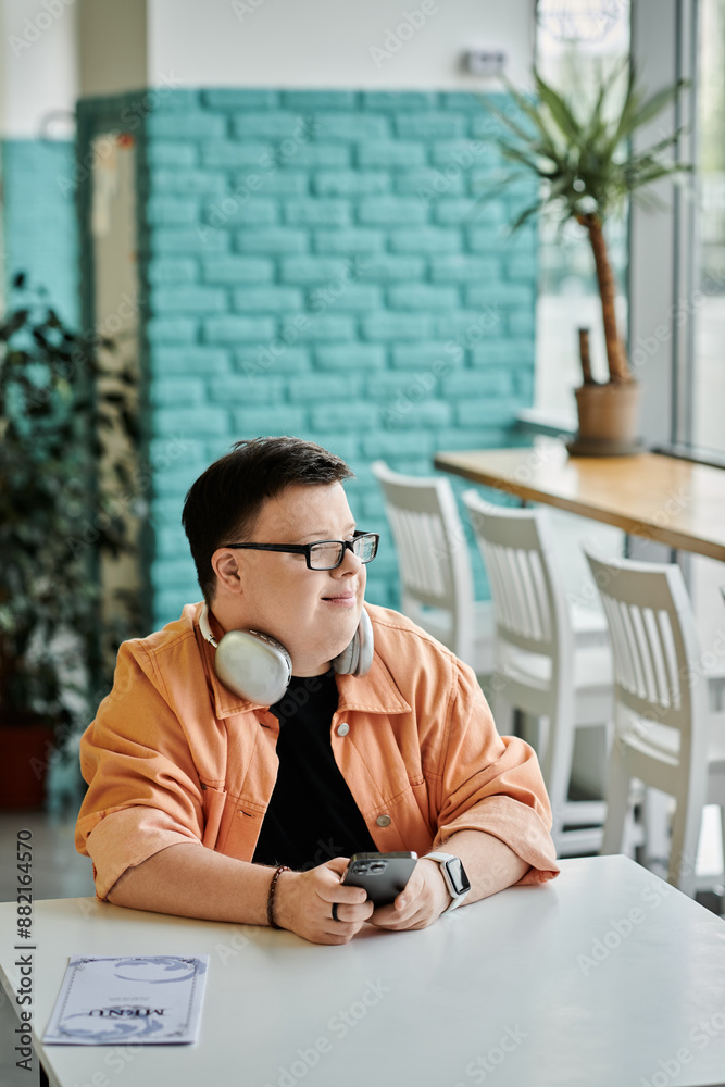 A young man with Down syndrome sits at a cafe table, deciding what to order. A young man with Down syndrome sits at a cafe table, deciding what to order.