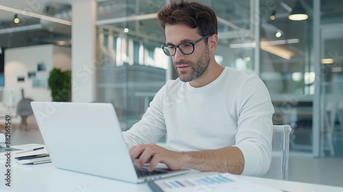 Ambitious Young Entrepreneur Engrossed in Laptop Work at Contemporary Office, with Clear Focus on Surroundings and Deep Depth of Field