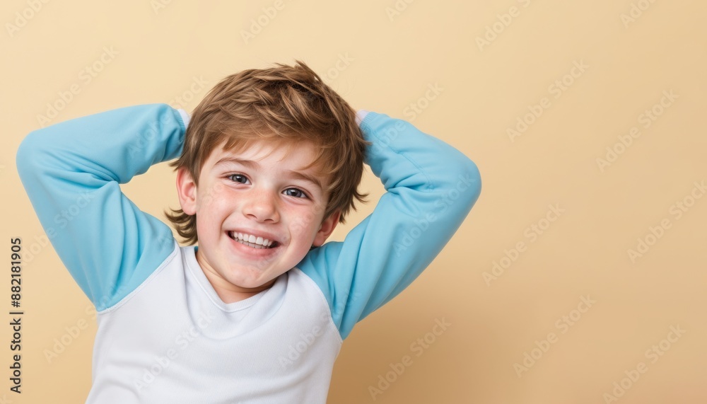 Smiling small boy, brown hair, wearing blue and white shirt, with his hands behind his head Smiling small boy, brown hair, wearing blue and white shirt, with his hands behind his head