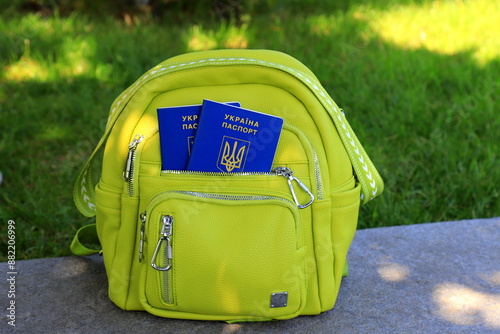 A passport of citizen of Ukraine with inscription in Ukrainian - Passport of Ukraine lies in green backpack. photo