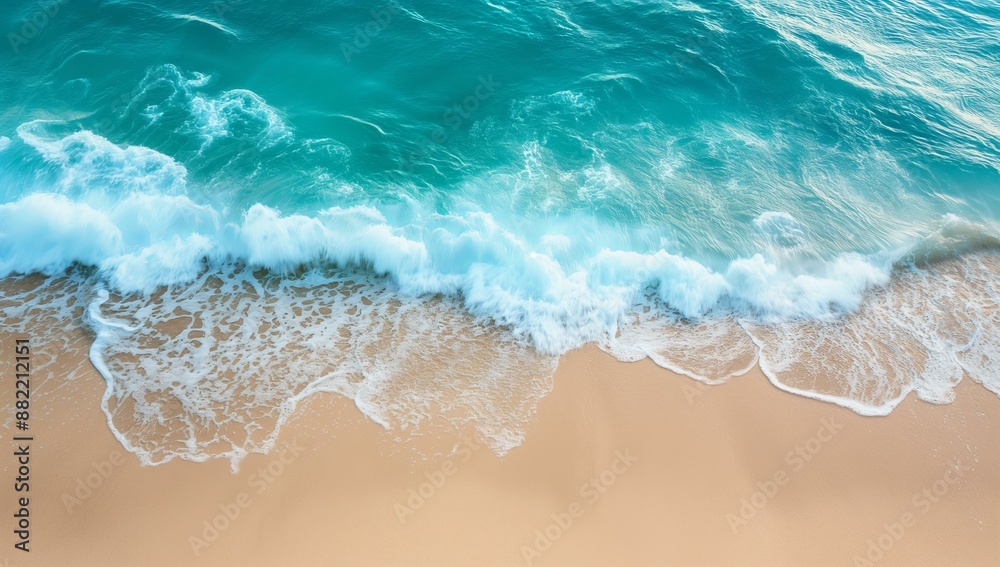 A top view of ocean waves gently lapping against a sandy shore. A top view of ocean waves gently lapping against a sandy shore.
