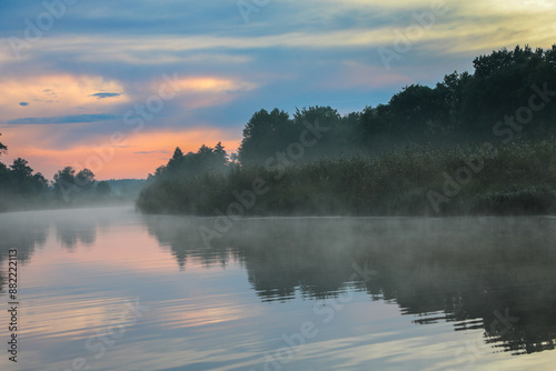 At sunset in summer, the river and forest are shrouded in fog. © Svitlana