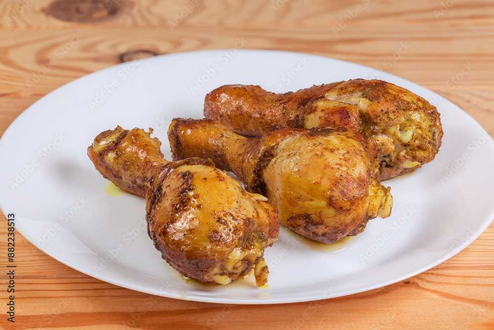 Baked chicken drumsticks on white dish, side view close-up Baked chicken drumsticks on white dish, side view close-up
