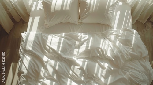  A bed featuring a white comforter and two pillions atop, encased in white sheets below photo