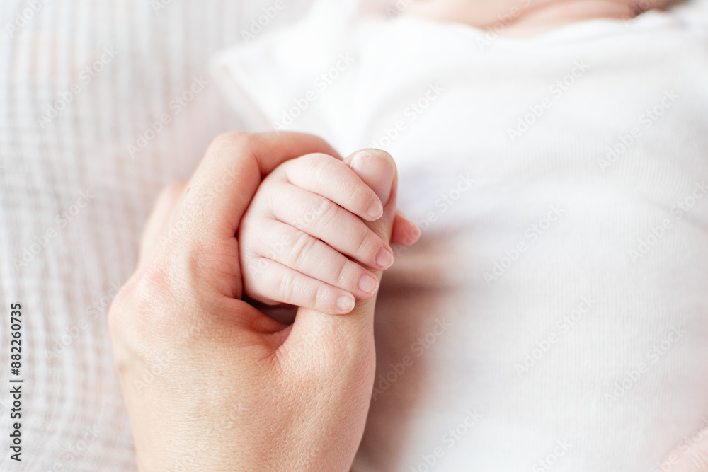 The newborn is holding the finger of the mother on a white background. The newborn squeezes a finger. Family and home concept. Healthcare, pediatrics. The newborn is holding the finger of the mother on a white background. The newborn squeezes a finger. Family and home concept. Healthcare, pediatrics.