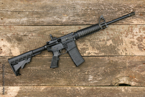 AR15 assault rifle with an adjustable stock on the background of old boards. Right side.