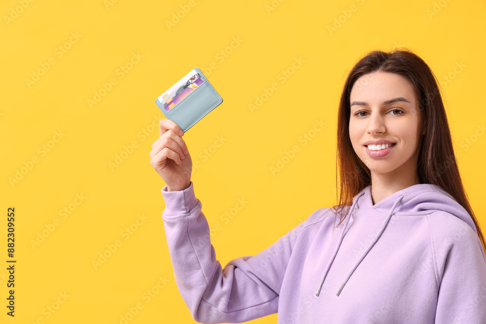 Woman with credit card holder on yellow background Woman with credit card holder on yellow background