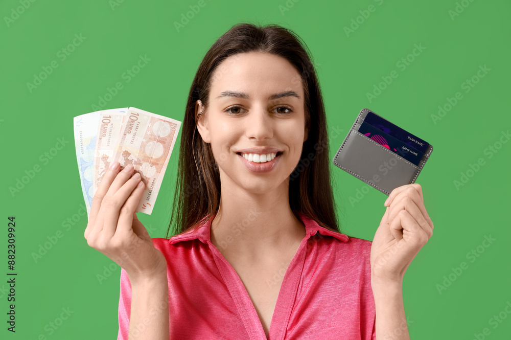 Happy young woman with credit card holder and cash on green background Happy young woman with credit card holder and cash on green background